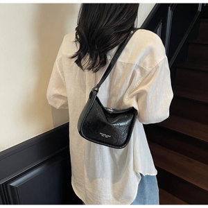 Detail of black glossy wrinkled texture underarm bag with silver logo and hardware