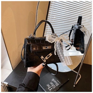 Close-up of black crocodile pattern Kelly bag with pearl and lace bow decorations