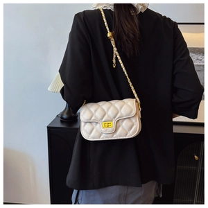 On-body view of quilted chain shoulder bag with gold sphere detail and metal lock