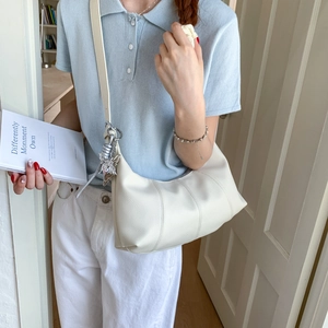 Detail of off-white lychee texture bag featuring a silver butterfly pendant accessory