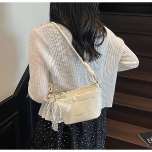 Detail of cream white pleated shoulder bag with lace pearl bow and front snap pocket