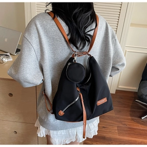 Black nylon backpack with brown straps and detachable coin purse on a model
