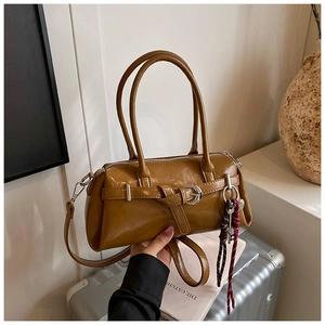 Detail view of caramel brown leather handbag with silver buckles and a woven rope charm