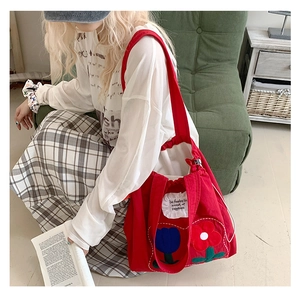 Detail of red canvas tote bag featuring floral appliqué and decorative ruffle label