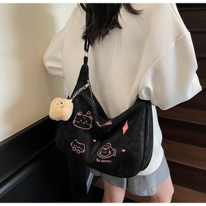 Detail view of black crossbody dumpling bag featuring pink cat embroidery and fluffy pendant