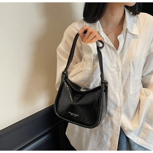 Detail of black glossy wrinkled texture shoulder bag with silver turn-lock and logo