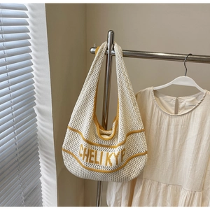 Detail of hollow-out knit tote bag with yellow CHELI KYP lettering and shoulder strap