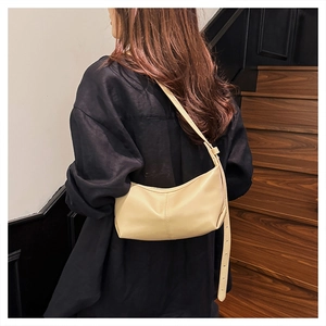 Model wearing a beige crescent dumpling bag with fine stitching on a vintage staircase