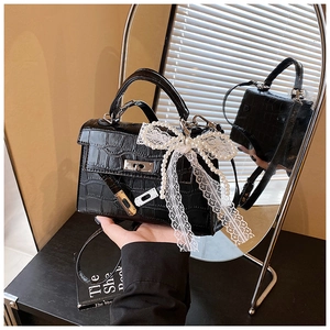 Detail of black crocodile embossed kelly bag with a large pearl lace bow charm