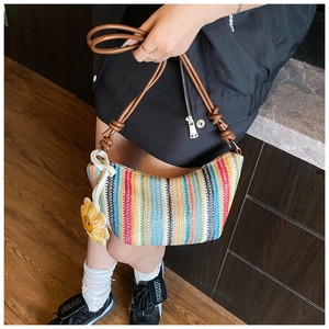 Detail of colorful striped straw bag with brown leather knotted strap and flower charm