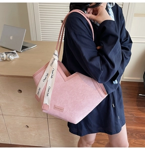 Close-up of pink tote bag featuring textured leather and white branded silk handle detail