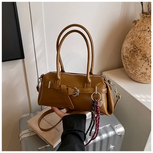 Detail of a brown faux leather handbag featuring metal buckles and woven rope accessory