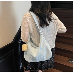 Close-up of light blue crossbody bag with cute cartoon embroidery and plush pendant