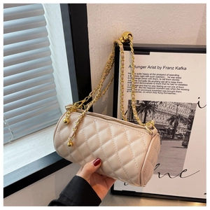 Vue détaillée d'un sac cylindrique beige matelassé avec chaîne dorée et breloque boule