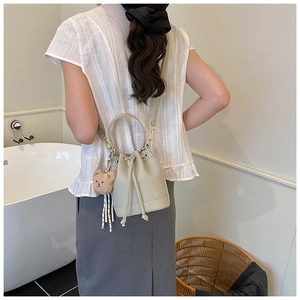 Light green drawstring bucket bag with bear charm shown on a shoulder