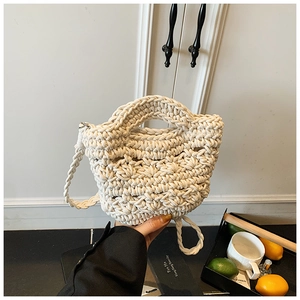 Macro shot of cream knit bucket bag showing intricate wavy textures and shoulder strap