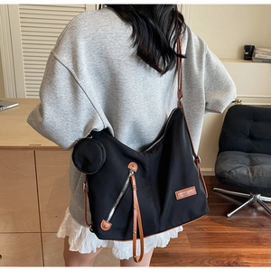 Detail of black nylon tote bag with brown leather trim and detachable small round pouch