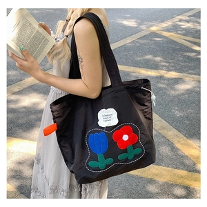 Detail of floral embroidery and fearless quote on large black nylon tote bag
