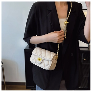 Close-up of quilted beige crossbody bag with gold chain strap and metal lock detail