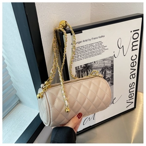 Détail du sac cylindre matelassé beige avec chaîne dorée et boule de réglage