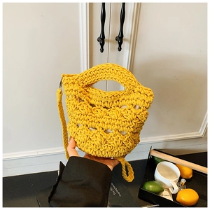 Detail of yellow hand-woven knit bucket bag featuring hollow mesh and matching strap
