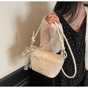 Close-up of beige wrinkled texture bag with pearl and lace bow charm detail