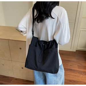 Close-up of black nylon bucket bag with adjustable drawstring closure and wide strap