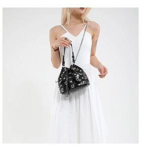 Detail of black drawstring bucket bag with silver metal studs and chain strap