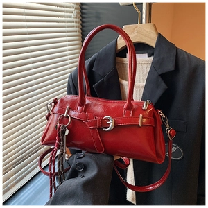Close-up of red glossy vintage handbag with silver metal buckle and decorative keychain