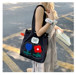Detail of floral canvas tote bag featuring floral patch and fearless slogan embroidery