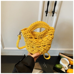 Close-up of handmade yellow knitted bucket bag with metal hooks for beach vacation