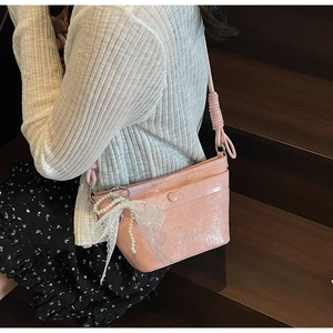 Pink pleated leather bucket bag with white lace bow and pearl charm detail