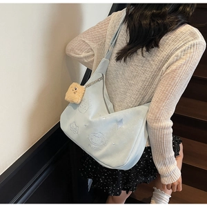 Close-up of light blue crossbody bag with cat embroidery and plush square pendant