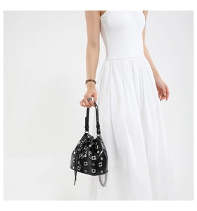 Detail of black drawstring bucket bag with silver metal studs and chain shoulder strap