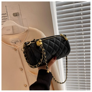 Détail du sac cylindre noir matelassé avec chaîne dorée et boucle à bille ajustable