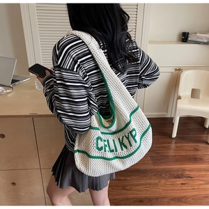 Detail of white knit tote with green stripes and CELIKYP lettering for casual wear