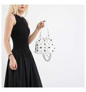 Close-up of white bucket bag with silver metal studs and drawstring closure details