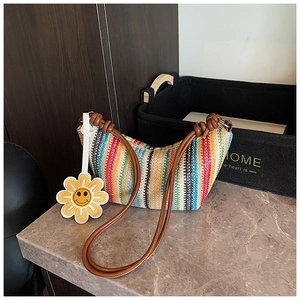 Detail of colorful striped woven tote bag with brown handles and sunflower charm