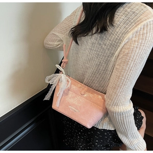 Detail of pink patent leather bucket bag with glossy crinkle texture and pearl charm