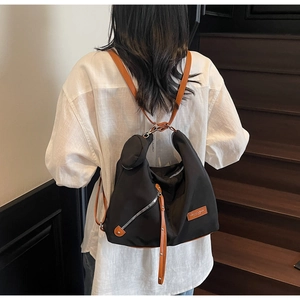 Detail of multi-functional black nylon backpack with brown leather straps and mini pouch