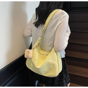 Close-up of cat and fish bone embroidery on a yellow crescent-shaped shoulder bag