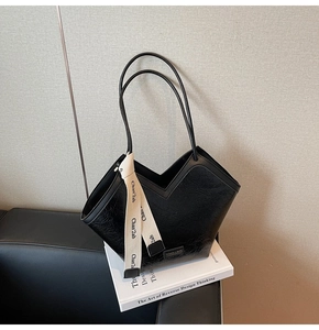 Detail of black tote bag with unique crinkle texture and elegant cream logo ribbon