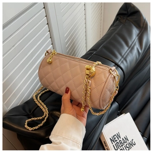 Détail du sac cylindrique matelassé rose avec chaîne dorée et boule en métal perlé
