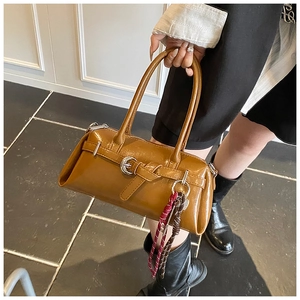 Close-up of caramel square handbag with metal buckle and woven strap accessory detail