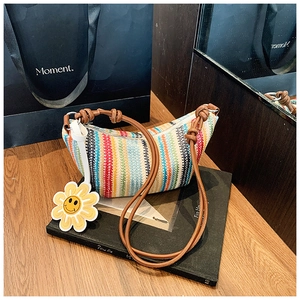 Detail of colorful striped straw bag with leather strap and sunflower charm