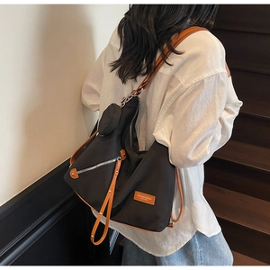 Detail of large black tote bag featuring brown leather straps and orange brand patch