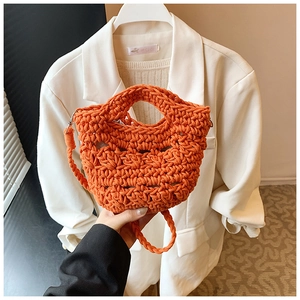Detail of orange hand-woven knit bucket bag featuring a hollow mesh texture and strap