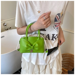 Détail du mini sac seau vert avec un nœud en cuir et un pendentif en forme de cœur