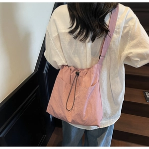 Detail of pink drawstring bucket bag showing lightweight textured fabric and adjustable strap