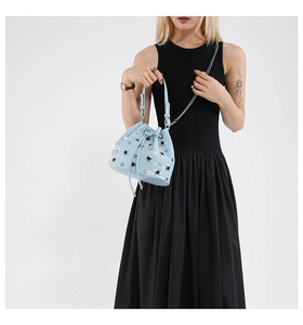 Close-up of light blue studded bucket bag with silver rivets and drawstring closure